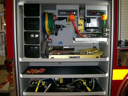 Open side compartment showing mounted rescue tools and shelf storage