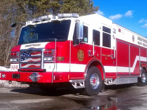 Front left exterior view of a heavy rescue truck with chrome bumper, crew cab, and long side compartments.