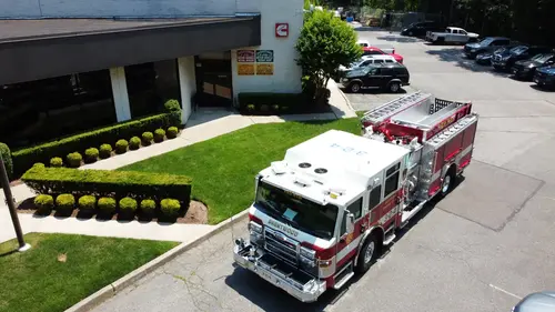 Pierce pumper aerial front-left view parked outside with roof ladders and hosebed