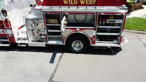 Pierce pumper aerial officer-side view with open side compartments and equipment bays