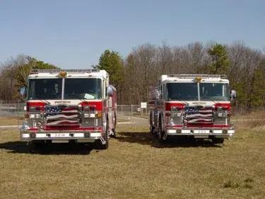 Front view of two pumpers parked side by side showing grilles and warning lights