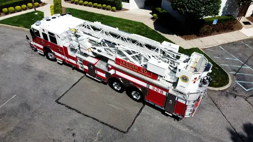 Pierce tower ladder elevated side view showing tandem rear axles and aerial structure