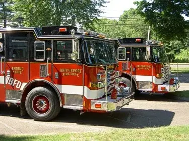 Front-left lineup view of two pumpers showing cab faces and side body sections.