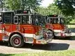 Front-left thumbnail view of two pumpers parked together on a driveway.