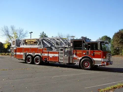 Driver-side profile view showing long ladder body and tandem rear axles