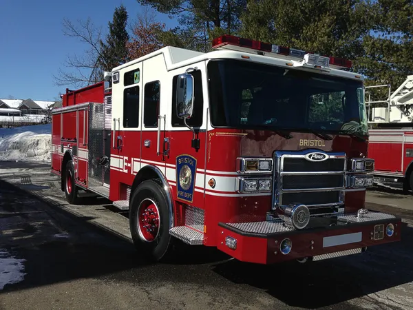 Front-right exterior view of a pumper with enclosed cab, side pump panel section, and body compartments.