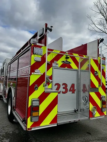 Rear-left close view showing chevron striping, rear compartment door, and warning lights
