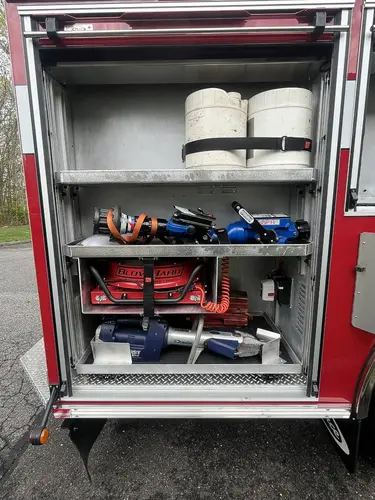 Open side compartment showing hose rolls, cribbing blocks, and hydraulic rescue tool storage