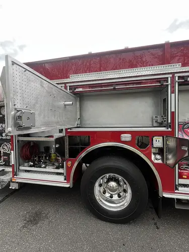 Open upper side compartment over rear wheel with side door raised and wheel area visible
