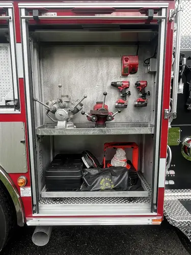 Open side compartment showing hand tools, cordless drills, and charger storage