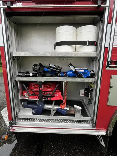 Open side compartment showing nozzles, handline tools, and shelf-mounted equipment