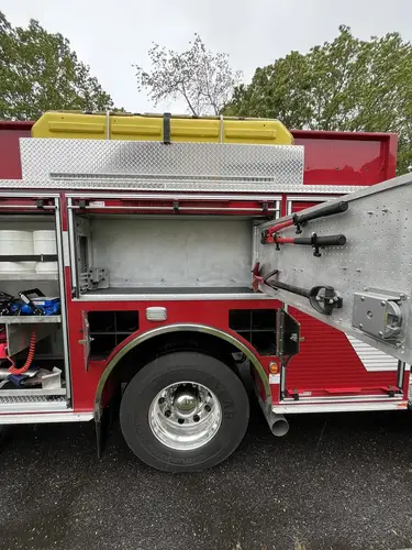 Open upper compartment above rear wheel with door-mounted tools and empty storage bay