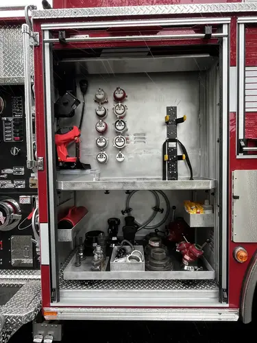 Open side compartment showing hose adapters, valves, and fittings on shelves