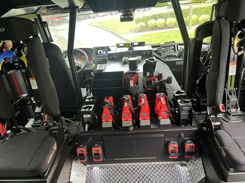 Cab interior rear-to-front view showing center console, mounted battery tools, and crew seats
