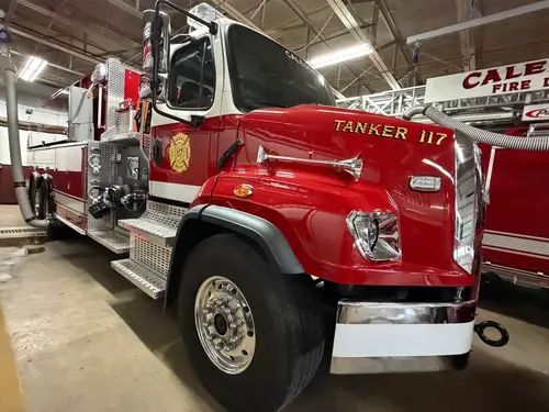 Tanker front-right exterior view in apparatus bay showing side pump panel and wheel area
