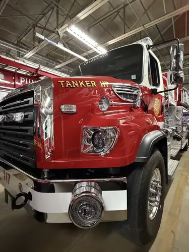 Front-right close-up showing bumper-mounted siren, headlight, and hood lettering