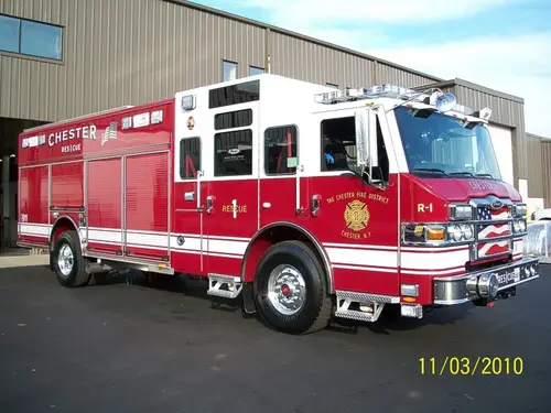Front-right exterior view of a rescue truck with enclosed cab, long side compartments, and wheel area.