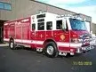 Wide front-right view of the rescue truck parked by the building with full side body visible.