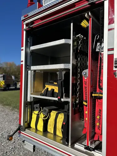 Rear side compartment doors open with storage shelves and yellow gear bags