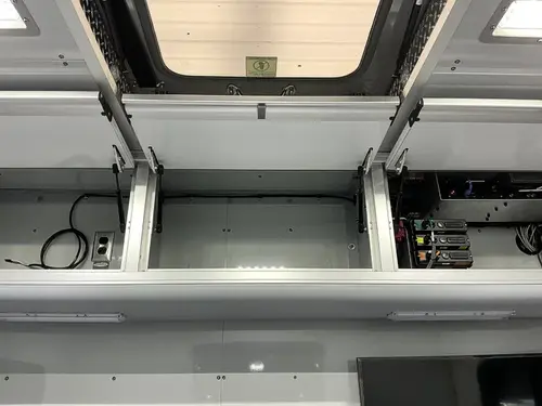 Upper interior storage compartment open with charger dock and empty shelves
