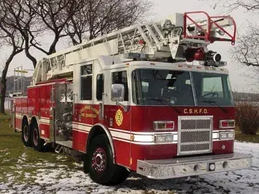 Aerial ladder truck front-left exterior view showing enclosed cab and ladder assembly