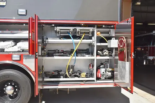 Open full-width side compartment showing tools, hoses, and shelf-mounted gear