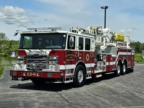 Aerial ladder truck front-left exterior view showing enclosed cab and ladder bed