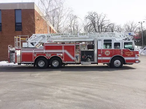Driver-side full profile showing ladder bed, pump panel area, and tandem rear axles