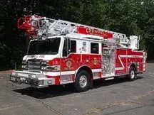 Tower ladder front-left exterior view showing enclosed cab and ladder bed