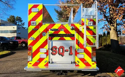 Rear view showing red-and-yellow chevrons, rear lights, and tailboard