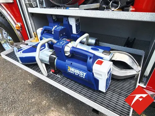 Open lower side compartment showing mounted rescue power units on tray