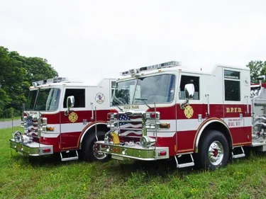 Two-pumper lineup front-quarter view showing white cabs and red bodies