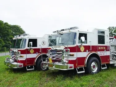 Two-pumper lineup front-quarter view showing white cabs and red bodies