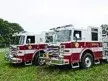 Two-pumper lineup front-quarter view showing white cabs and red bodies