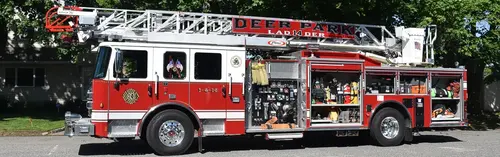 Aerial ladder truck side profile view showing full apparatus and open compartments
