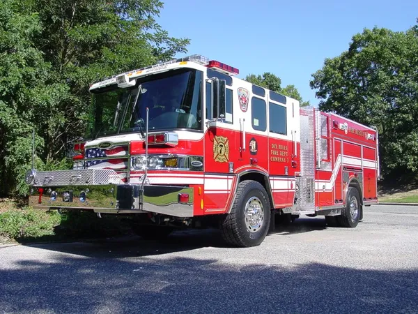 Front-left exterior view of a rescue pumper showing enclosed cab, side pump panel section, and rear body compartments.