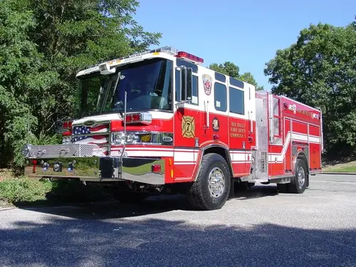 Front-left exterior view of a rescue pumper showing enclosed cab, side pump panel section, and rear body compartments.