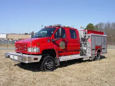 Front-left exterior view of a rescue pumper with commercial cab, side pump panel, and rear body compartments.