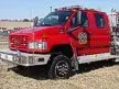 Wide front-left view of the rescue pumper parked on grass with commercial cab and side body visible.