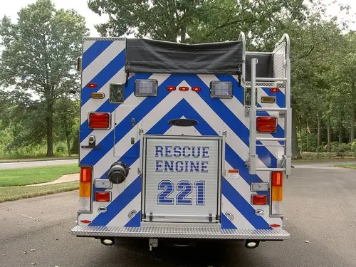 Rear view showing blue-and-white chevrons, rear door panel, and warning lights