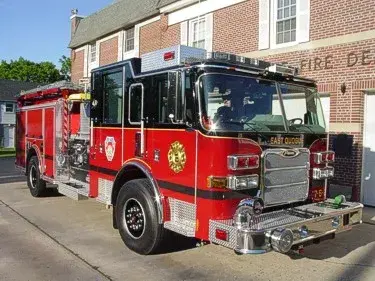 Front left exterior view of the pumper with chrome bumper, cab lights, and side pump controls visible.