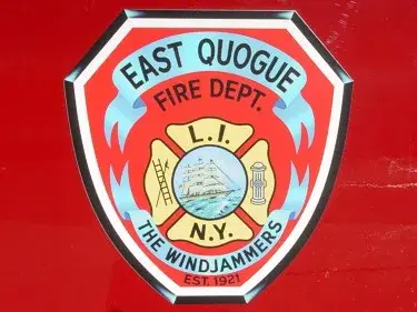 Close-up of a shield-style side door emblem on red paint with decorative fire service symbols.