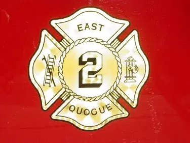 Close-up of a maltese-cross style company emblem with center number on red body panel.
