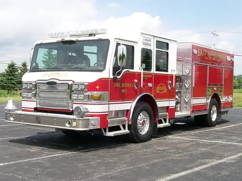 Front-left exterior view of a rescue pumper with enclosed cab, side pump panel area, and rear body compartments.
