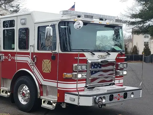 Pumper front-left exterior view parked roadside with side compartments closed