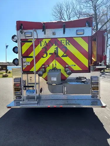 Rear view showing red-and-yellow chevrons, rear lights, and tailboard