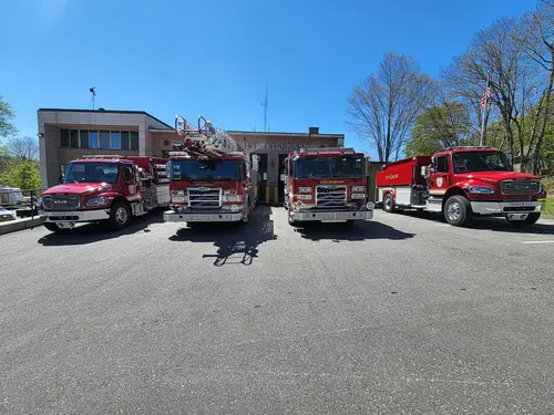 Wide station-lot view showing multiple apparatus parked in front of building