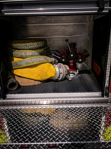 Open lower side compartment showing yellow gloves and folded hose