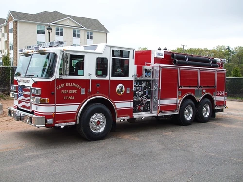Front left side view showing cab doors, pump panel, roll-up compartments, and rear tandem axles.