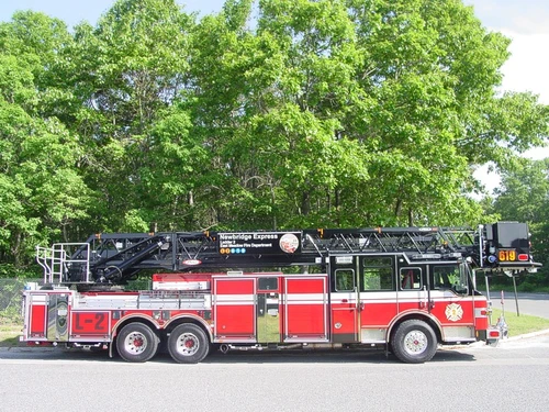 Driver-side full profile showing the stowed aerial ladder, bucket section, and tandem wheel layout.